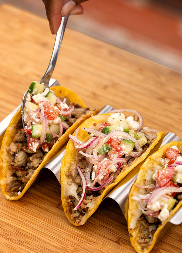 Turkey crispy tacos topped with veggies, onions, and cheese, served on a tray for a tasty meal.
