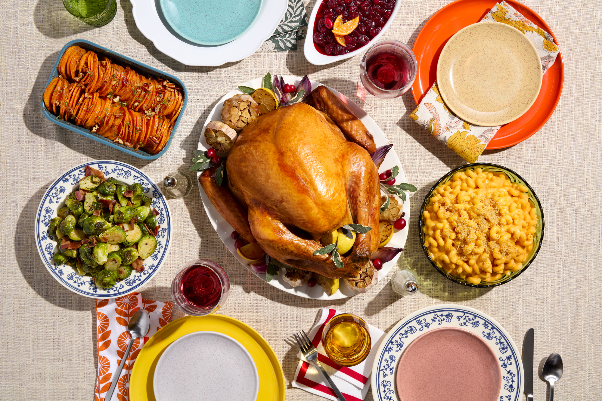 A roasted turkey with side dishes like sweet potatoes, mac and cheese, and Brussels sprouts.