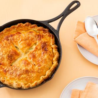 Leftover turkey recipe: a golden-brown pot pie with a flaky crust in a cast iron skillet. 