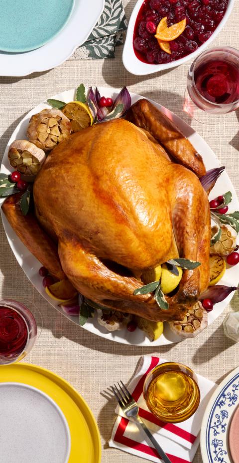 A roasted turkey with side dishes like sweet potatoes, mac and cheese, and Brussels sprouts.