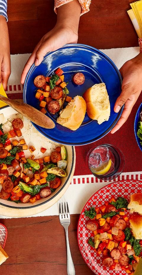 Two sets of hands serving up a Butterball smoked turkey sausage and sweet potato skillet dish.