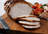 A seasoned, cooked, and sliced Butterball Turkey Breast displayed on a cutting board.