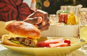 Turkey burger with cheese and watermelon slices on a plate at an outdoor summer cookout.