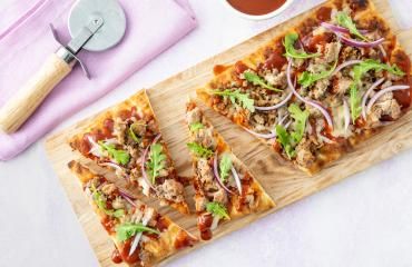 Slice of BBQ ground turkey flatbread pizza arranged on a cutting board.