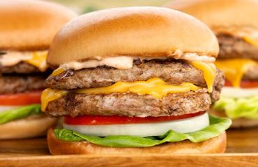 A close-up of a smashburger turkey burger with cheese, onion, lettuce, and tomato.