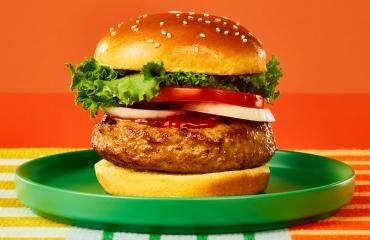 A Butterball lean ground turkey burger on a bun with lettuce, tomato, and ketchup.