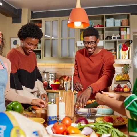 Family talking and laughing in the kitchen while preparing a meal