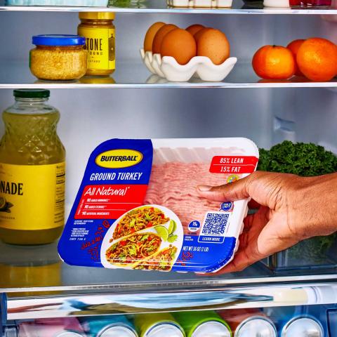 A person places a 1 pound pack of Butterball 85 percent lean ground turkey in a refrigerator.