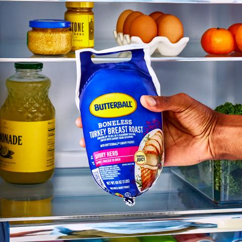 A person places a Butterball Savory Herb Boneless Turkey Breast Roast in a refrigerator.