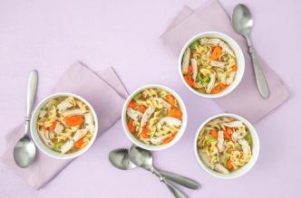 A comforting turkey soup recipe with egg noodles, carrots, and shredded turkey in white bowls.