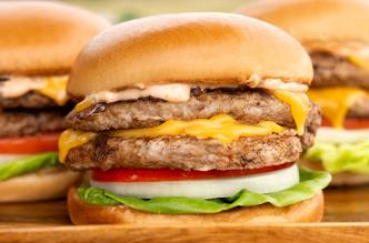 A close-up of a smashburger turkey burger with cheese, onion, lettuce, and tomato.