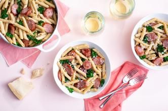 Lemon broccolini pasta with turkey sausage, served in bowls on a pink table setting.