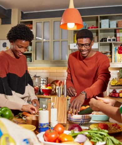 Family talking and laughing in the kitchen while preparing a meal