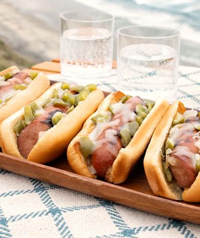 Image of Philly Cheesesteak Grilled Sausages on a tray by the beach.