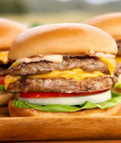 A close-up of a smashburger turkey burger with cheese, onion, lettuce, and tomato.