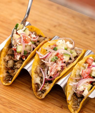 Turkey crispy tacos topped with veggies, onions, and cheese, served on a tray for a tasty meal.