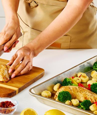 A person slices a Butterball turkey tenderloin with a chef's knife on a cutting board.