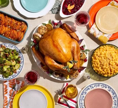 A roasted turkey with side dishes like sweet potatoes, mac and cheese, and Brussels sprouts.