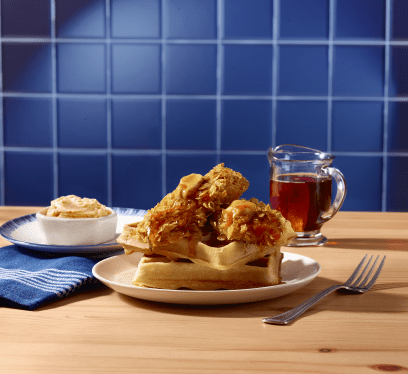 Cornflake crusted turkey tenderloin on a stack of waffles, drizzled with syrup and butter.