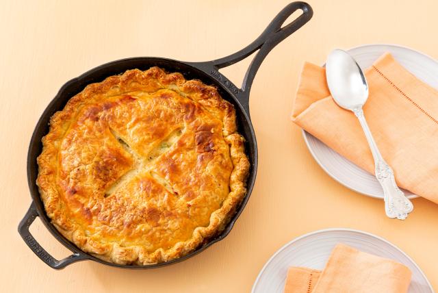 Leftover turkey recipe: a golden-brown pot pie with a flaky crust in a cast iron skillet. 