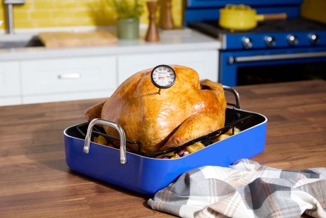 Turkey in a roasting dish with a meat thermometer sticking out.