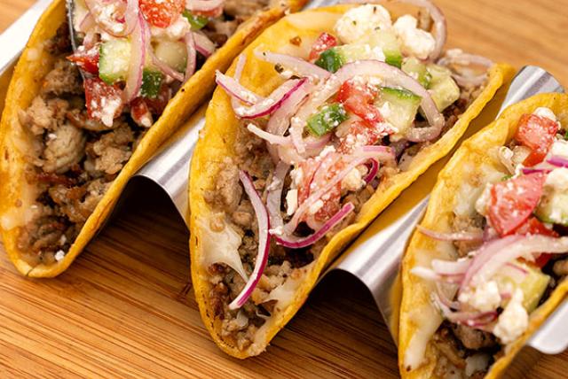 Turkey crispy tacos topped with veggies, onions, and cheese, served on a tray for a tasty meal.